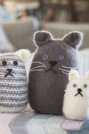 Three knitted cats of different sizes, two plain and one striped