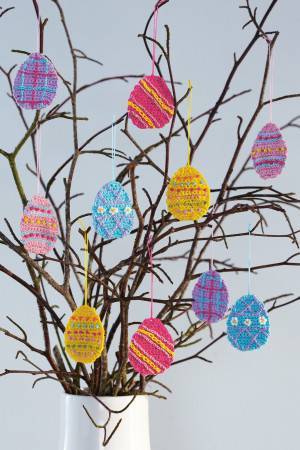 Vase of crocheted egg-shape decorations hanging from twigs