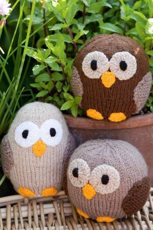 Three different knitted owls with yellow beaks and feet