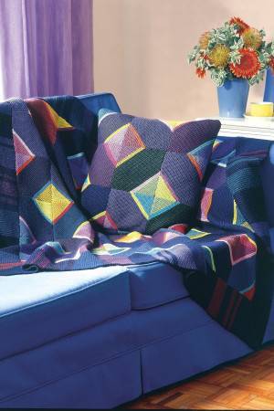 Bold knitted blanket and cushion with triangles within squares in different colours