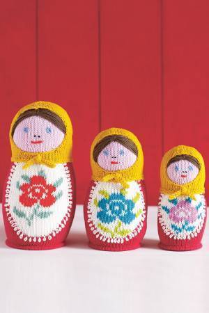 Three knitted Russian dolls with headscarves and floral motifs on bodies