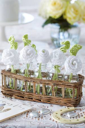 Basket of white crocheted flowers with green leaves for wedding breakfast table
