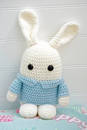 Crocheted white toy bunny wearing pale blue jacket with collar