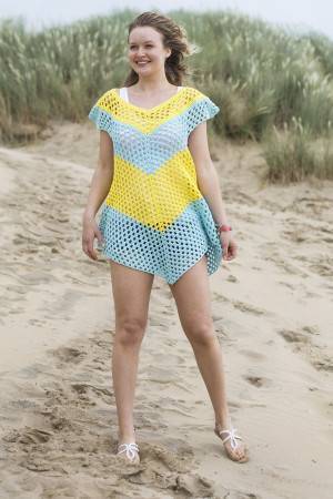 Lady on a beach wearing a bright poncho with chevron pattern
