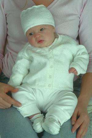 Baby wearing white knitted hat with matching booties